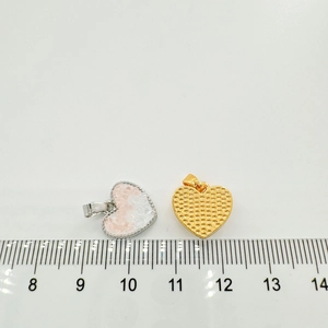 Close-up of 18k gold heart pendants in silver and gold with size reference scale