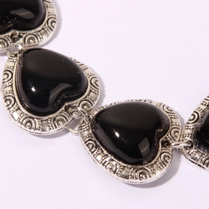 Detailed macro view of vintage heart-shaped black stones in ornate silver-tone settings