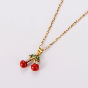 Close-up of a gold necklace with shiny red cherry pendants and green leaves