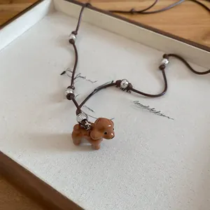Gros plan du pendentif caniche marron sur un collier cordon au fini émaillé soigné