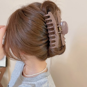 Detail view of a large matte brown hair claw clip securing a low bun hairstyle