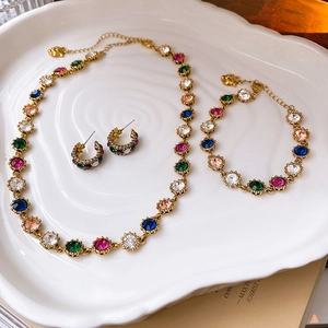 Detailed close-up of vintage baroque jewelry set with multi-colored gems on ceramic