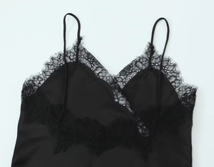 Close-up of elegant black satin fabric with intricate floral lace trim and slim straps