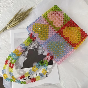 Close-up of colorful floral beaded shoulder bag with textured white fabric and magazine