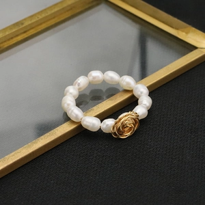 Dettaglio macro di anello con perle d'acqua dolce e rosa in filo d'oro su vetro