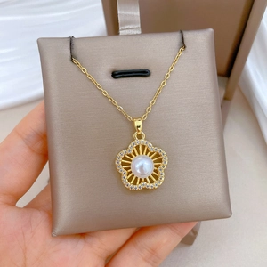 Close-up of gold flower pendant with white pearl and crystals on satin cushion