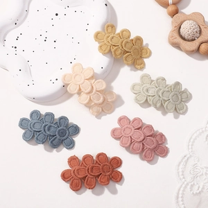Détail de barrettes à fleurs brodées en six couleurs pour enfants sur un plat blanc
