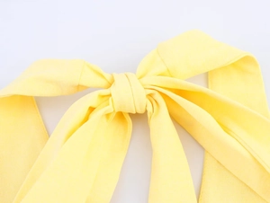 Detail shot of bright yellow knitted fabric featuring a delicate bow-tie halter neckline