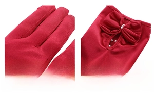 Dettaglio guanto in raso rosso con cuciture sottili, fiocco decorativo e perle bianche