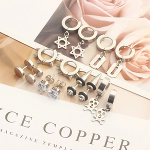 Detail view of silver stainless steel earring set with cross and skull charms on magazine