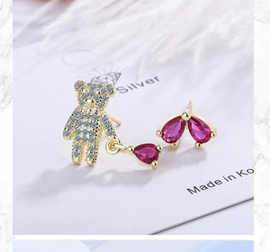 Detail of asymmetric bear earrings with sparkling purple pear-cut zircon crystals