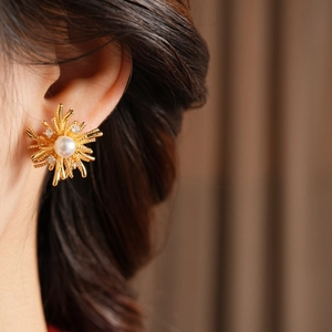 Detailed close-up of a zircon sunflower earring with pearl center on a female model