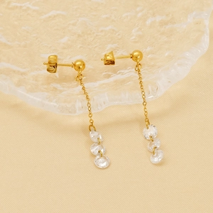 Elegant gold long tassel drop earrings with sparkling round zircon crystals on a glass tray
