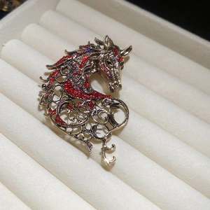 Macro view of vintage bronze horse brooch with red rhinestones in a beige velvet jewelry box