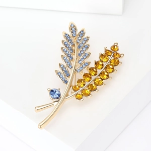 Detailed close-up of golden leaf brooch with sparkling blue and yellow gemstones