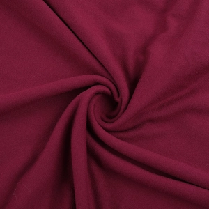 Macro shot of deep wine red knitted fabric texture with soft drape and spiral folds