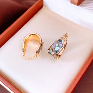 Detailed macro view of vintage 18K gold plated U-shaped earrings with colorful abalone shell