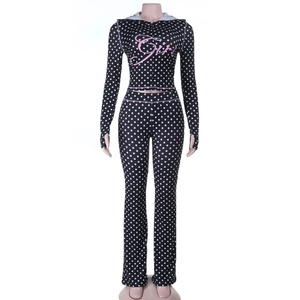Close-up of pink Girl lettering on black polka dot tracksuit with zipper detail