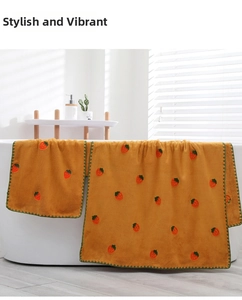 Detail of coral fleece towel set with strawberry embroidery draped over a bathtub