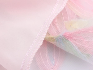 Close-up of pink 3D flower dress showing mesh fabric texture and hem sewing details