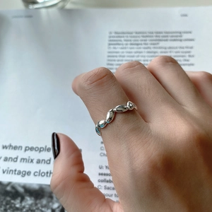 Close-up of minimalist sterling silver twisted ring on finger with artistic background