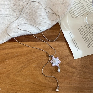 Close-up of snowflake pendant necklace with a drop pearl on a silver snake chain