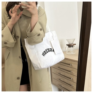 Mirror selfie showing large white canvas tote bag with FASHION text and matching pouch