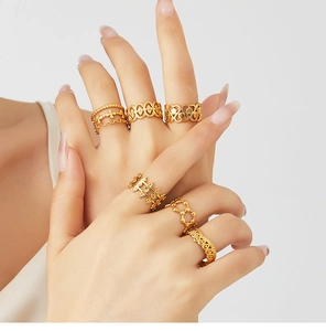 Detail of six gold-plated vintage crown rings with floral and cross patterns on a model's hand
