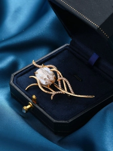 Detail of vintage baroque pearl brooch with copper zircons and floral branch design