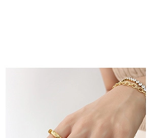 Dettaglio del bracciale a catena dorata e del bracciale tennis con zirconi al polso