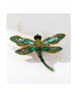 Close-up of vintage dragonfly brooch with green rhinestones and marquise gems