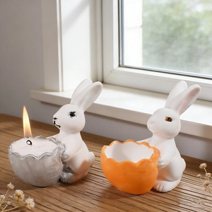 Close-up of Easter bunny silicone mold figurines holding candle shells on wood surface