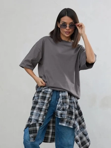 Dettaglio maglietta in cotone grigio scuro abbinata a una camicia a quadri in vita