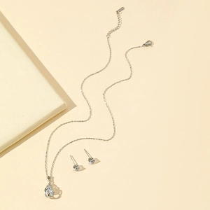 Silver twisted hollow waterdrop necklace and zircon earring set on a beige background