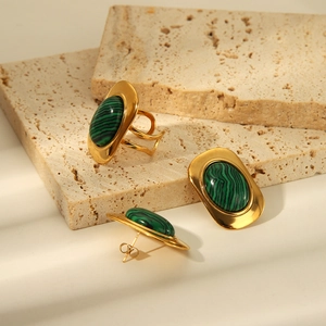 Golden stainless steel jewelry set with oval malachite stones on beige stone blocks