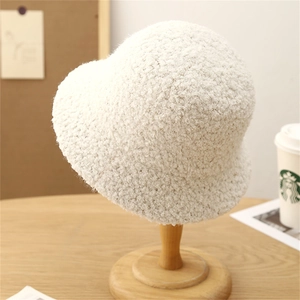 White fuzzy bucket hat for women with minimalist soft texture displayed on a wooden stand