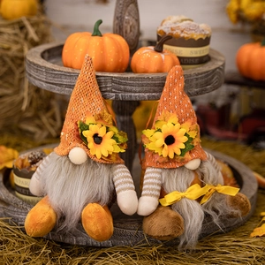 Detail of plush fall gnomes with orange knit hats and sunflowers on a tiered tray