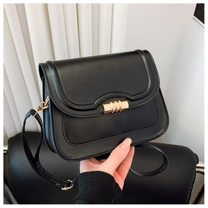 Détail d'un sac bandoulière noir avec boucle en métal doré et texture cuir matelassé