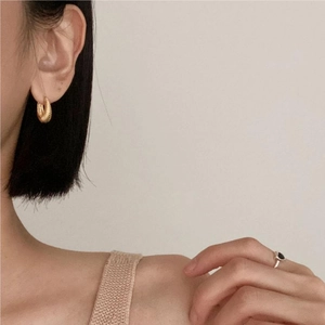 Detail of twisted gold croissant earrings and matching black stone ring on a model
