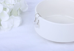 Macro detail of natural white agate earrings with S925 silver hooks on a porcelain bowl