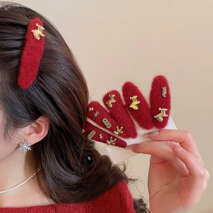 Detail of red plush hair clips set with golden festive metal charms and fuzzy texture