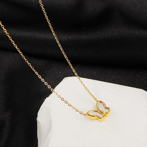 Elegant gold titanium butterfly necklace with white shell inlay on a white stone background