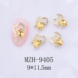 Vue macro de breloques ongles coeur 3D avec gravure love et zircone jaune brillant