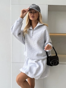 Detail of light gray oversized half-zip sweatshirt with metal zipper and soft fabric texture