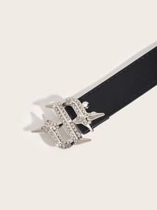 Detail of black leather belt featuring a silver S-shaped buckle with sparkling rhinestones