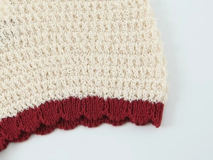 Detailed close-up of knit texture with beige main body and dark red contrast trim