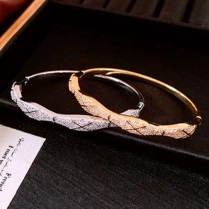Détail de bracelets entrelacés argent et or avec motif matelassé et cristaux étincelants