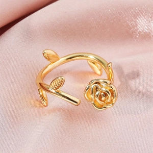 Detailed view of adjustable golden rose ring with leaves on soft pink silk fabric