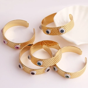 Détail du bracelet Evil Eye doré en forme de C avec breloques en émail coloré sur coquille
