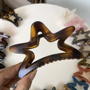 Macro detail of amber star-shaped hair claw clip with cutout hollow design and tortoise finish